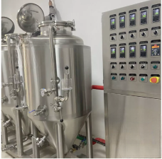 Stainless steel brewing tanks next to a control panel with buttons and switches.