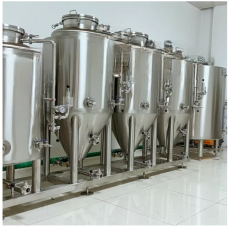 A row of stainless steel fermentation tanks in a clean, industrial facility.