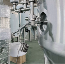 Close-up of a metal pipe and valve on a stainless steel industrial tank.