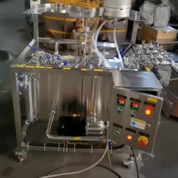 Stainless steel processing machine with control panel and various connected tubes.