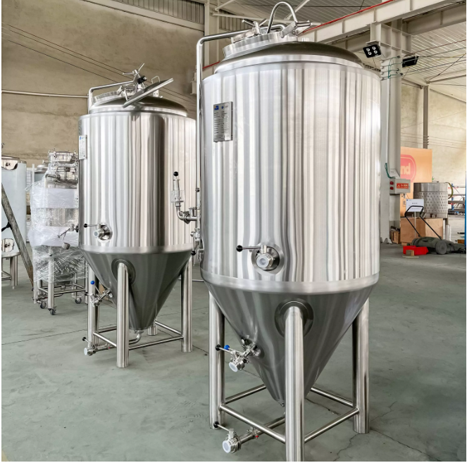 Two large stainless steel fermentation tanks in a spacious industrial setting.
