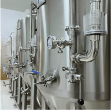Stainless steel brewing equipment in a modern facility, showing valves and gauges.