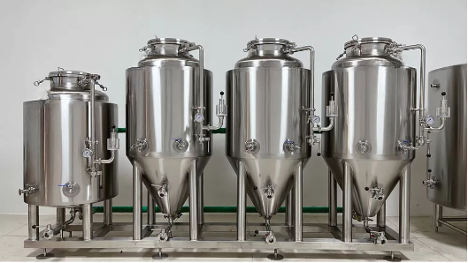 Three stainless steel fermentation tanks of varying sizes in a row.