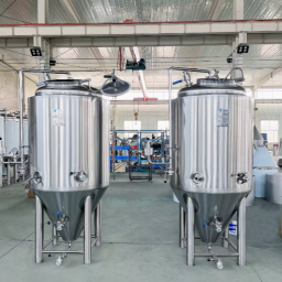 Two stainless steel fermentation tanks in a factory setting.